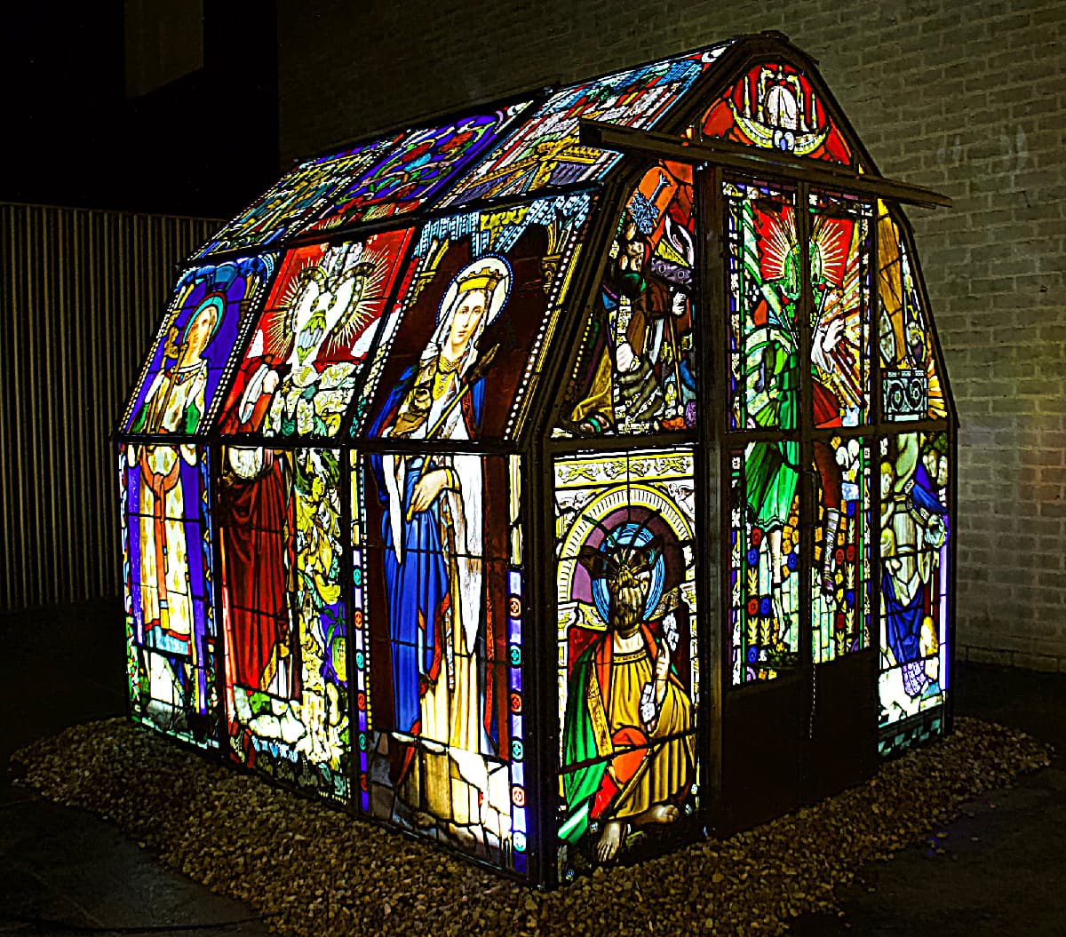 Repurposed Stained Glass Comprises a Disorienting Illuminated Greenhouse Bathed in sunlight by day and illuminated by LED bulbs at night.