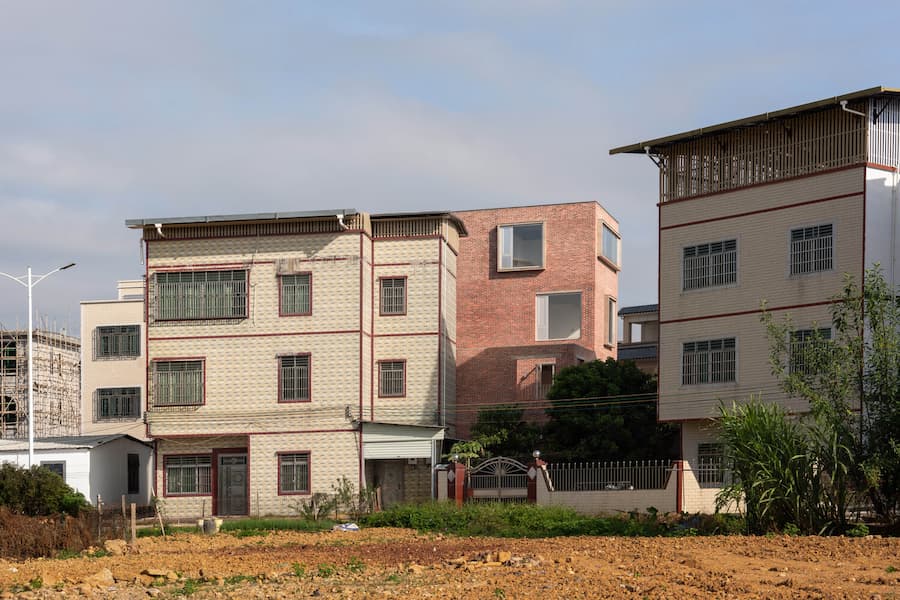contrast between new brick house and traditional village buildings