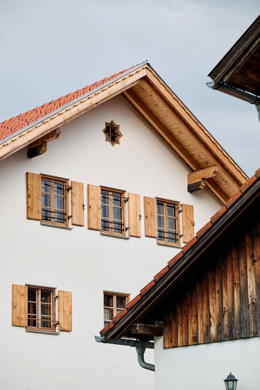 traditional farmhouse facade with timber shutters plaster wall and roof eaves detail