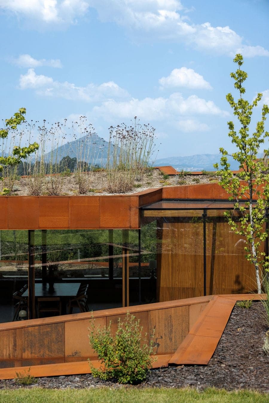 corten steel roof and planted surface blending house into surrounding terrain