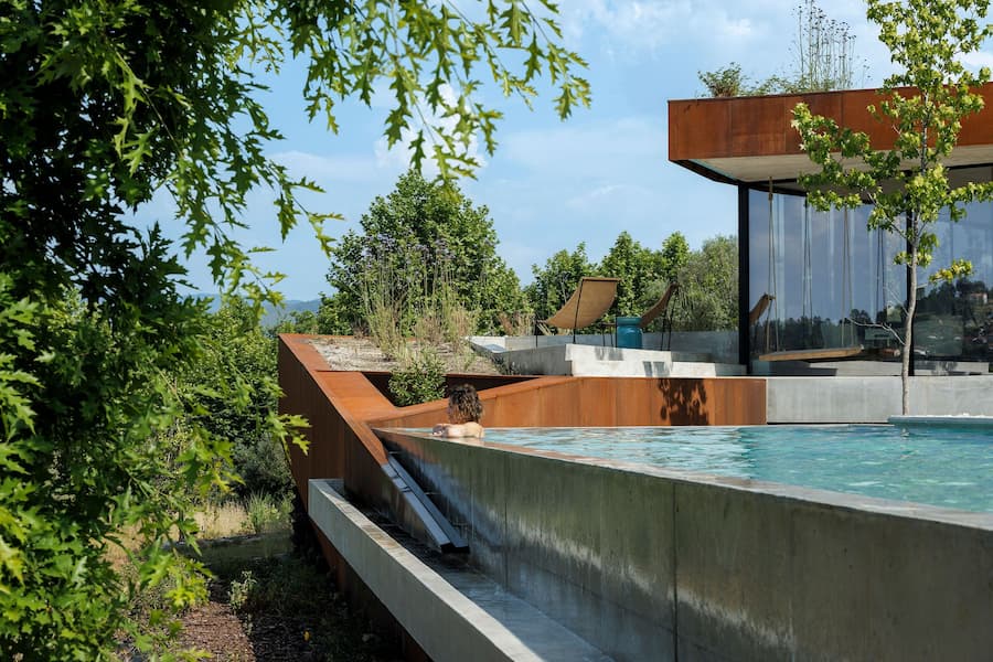 corten steel terrace and pool integrated into hillside architecture
