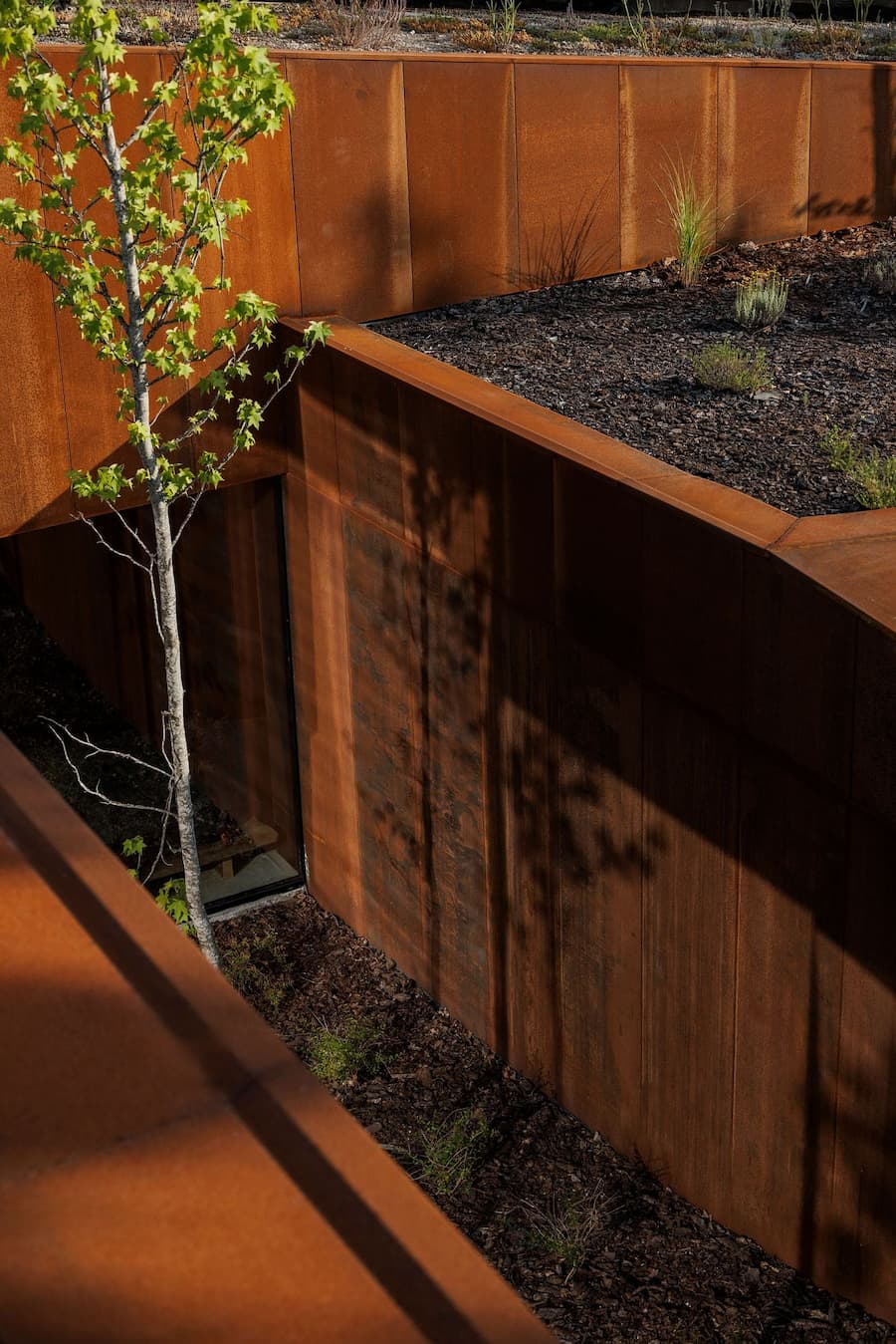 window opening framed by corten steel connecting interior and landscape