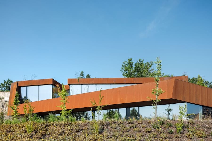 sunken courtyard space enclosed by corten steel walls within the terrain