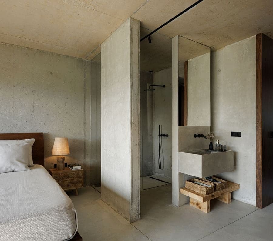 bedroom with exposed concrete walls and integrated open bathroom layout behind partition