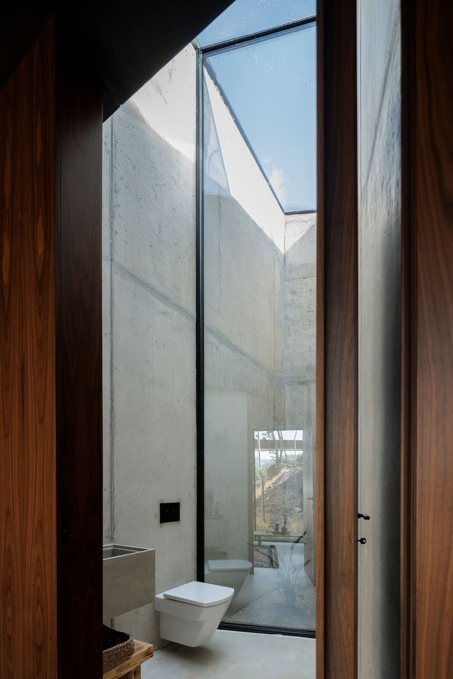 bathroom space with vertical skylight and concrete walls forming a narrow light well