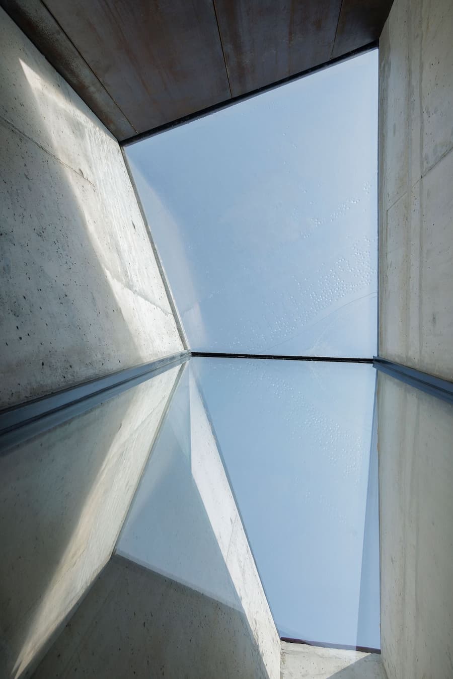 geometric skylight opening creating vertical light void between concrete surfaces