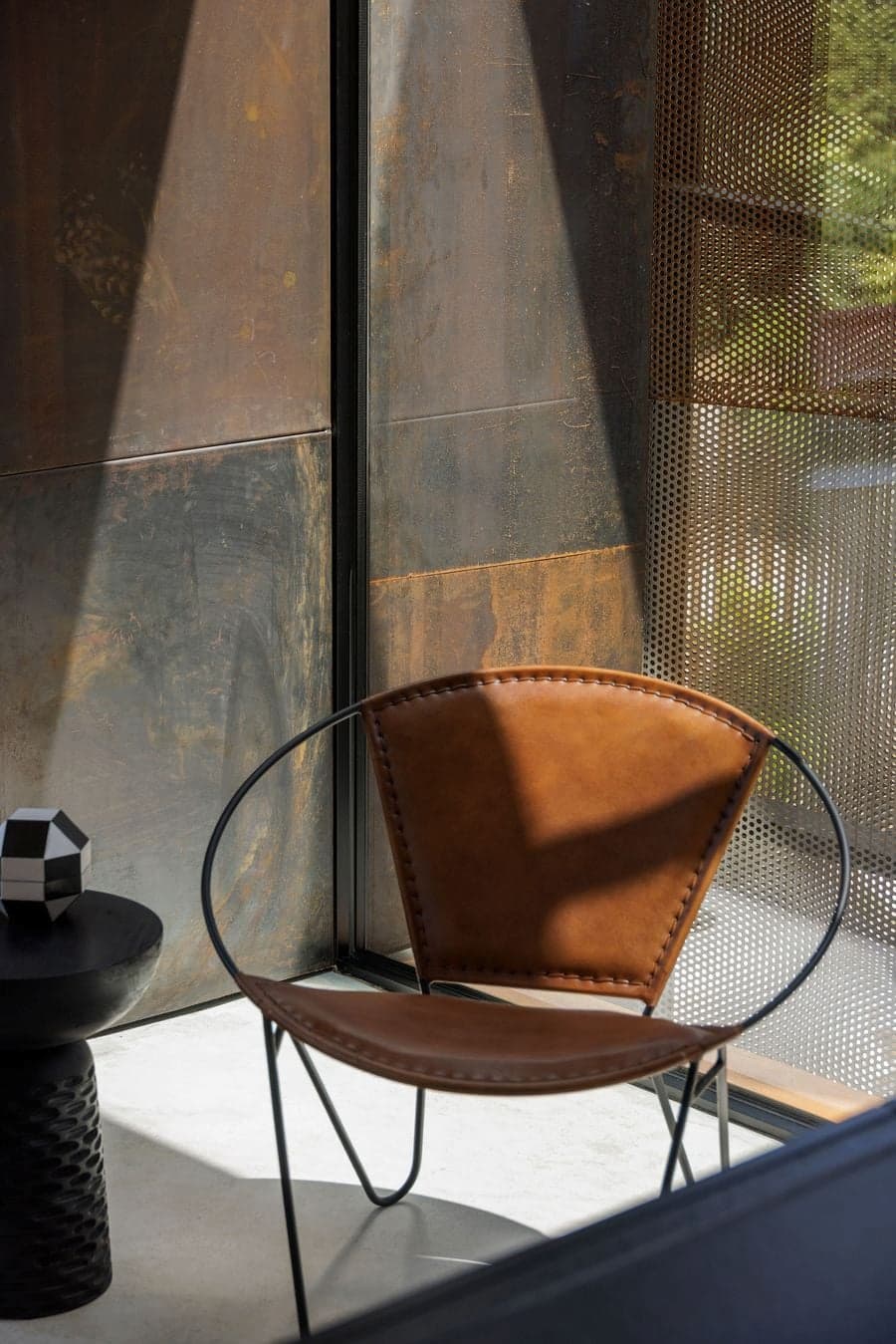 close up of leather chair with filtered light passing through perforated steel surface