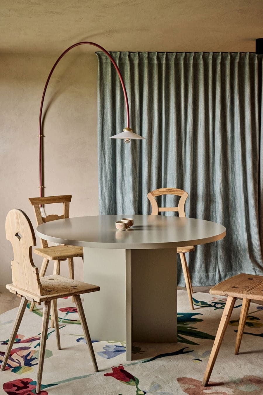 round dining table surrounded by wooden chairs and soft curtain backdrop