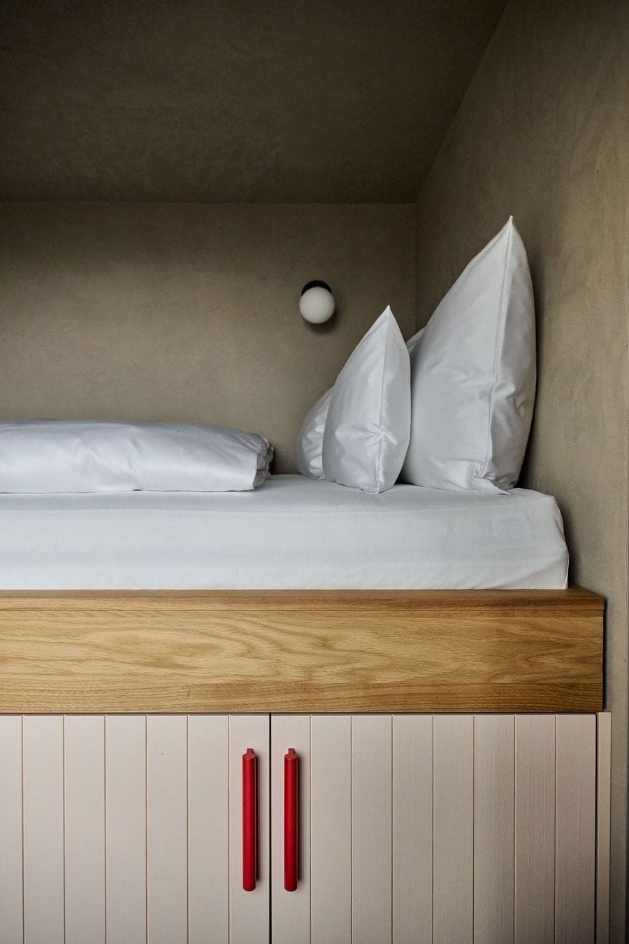 minimal sleeping space with simple bedding and plaster wall enclosure