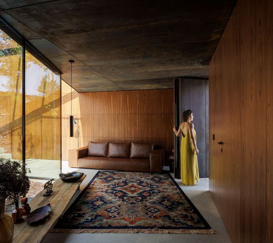 living room with corten steel ceiling and wood panels forming layered material contrast