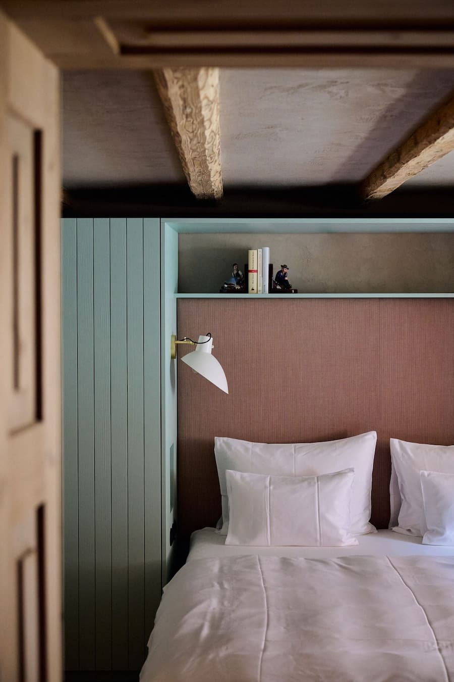bedroom interior with integrated headboard soft textiles and exposed wooden beams creating layered spatial depth
