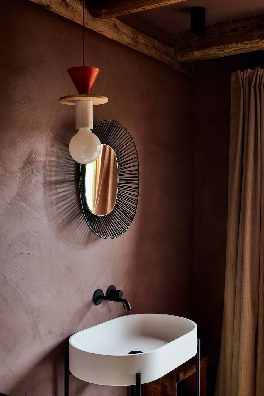bathroom with textured plaster walls contrasted by a minimal white sink and sculptural lighting