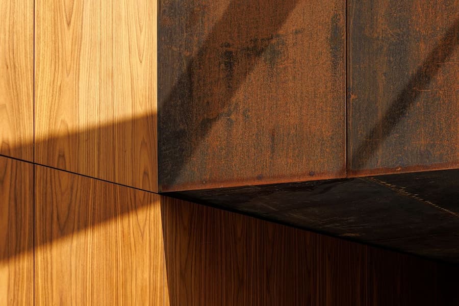 junction of corten steel cladding and wood panels expressing controlled material contrast