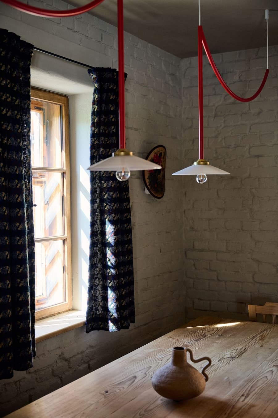 minimal pendant lights with red cables introducing a bold visual accent within a neutral interior