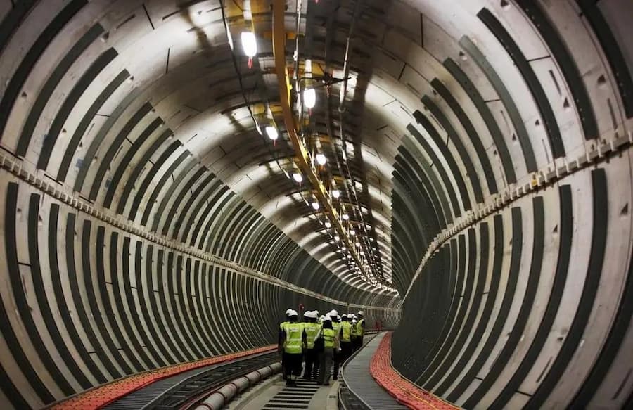 workers inside a large underground tunnel, revealing hidden urban infrastructure systems and spatial depth