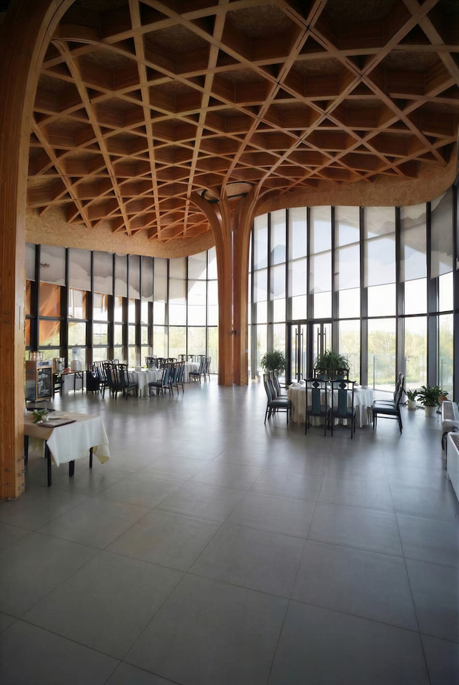 interior dining space with timber grid roof and glass facade facing lake