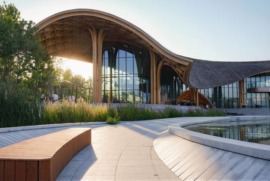 overall architectural form showing flowing timber roof and site integration 