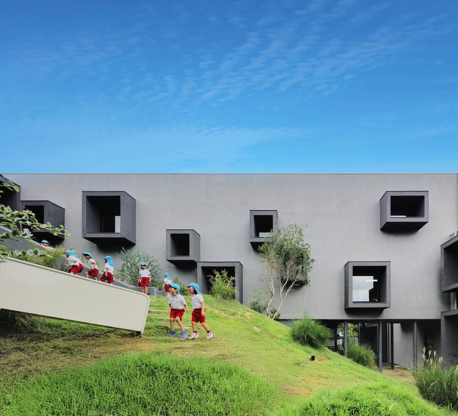 children moving through sloped landscape integrated with contemporary educational architecture