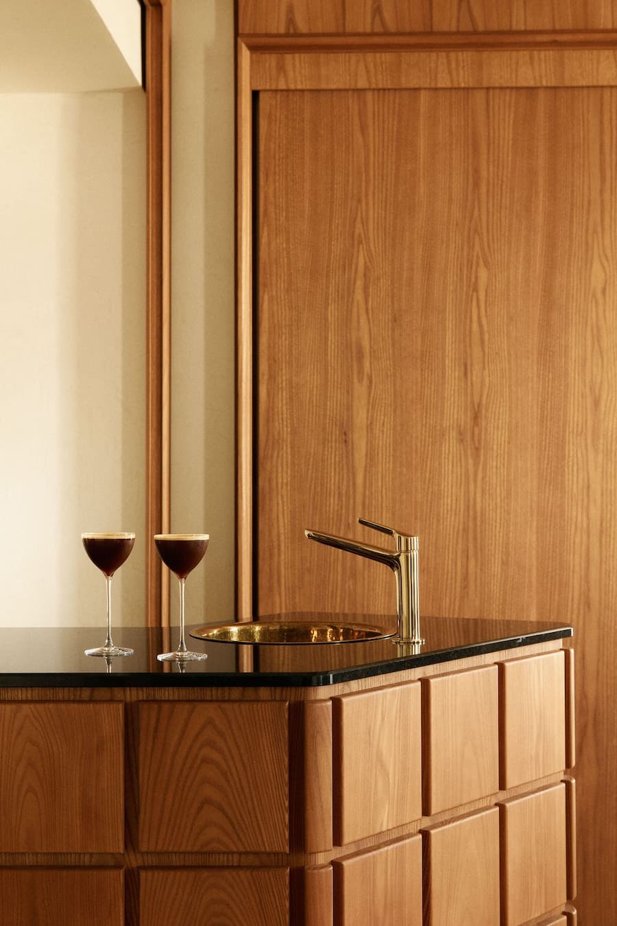 Custom wood kitchen island and brass sink detail at La Fondation