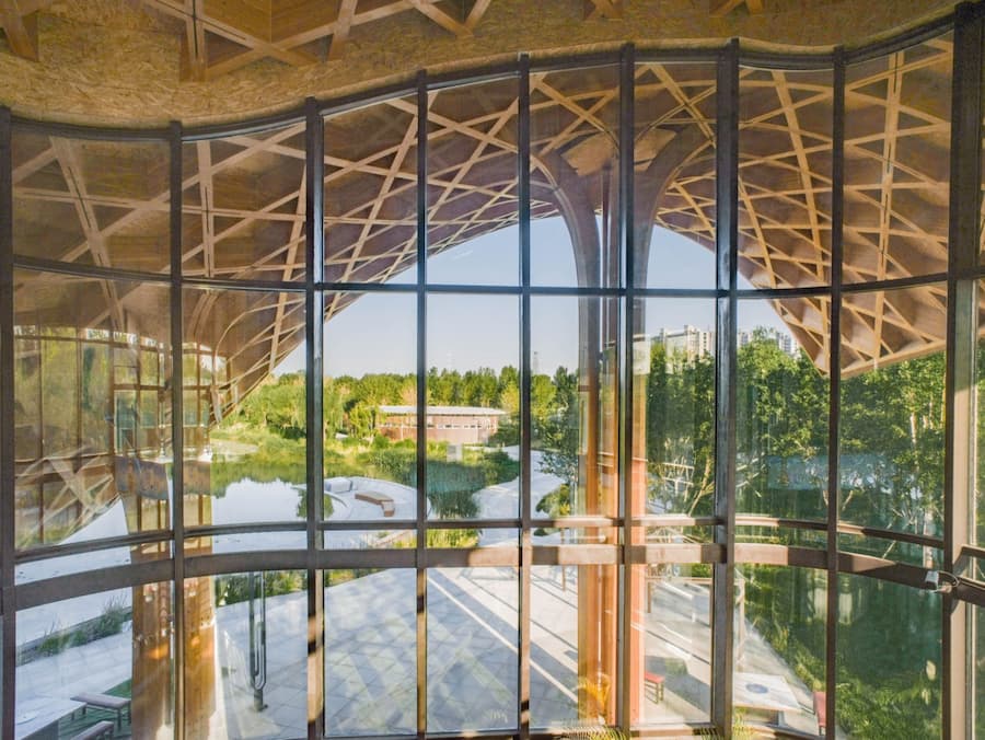 interior space showing timber columns and glass facade toward landscape