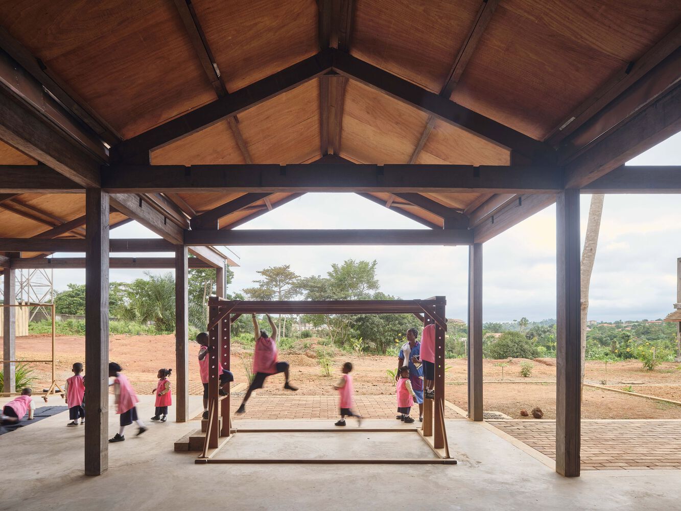 children interacting within open timber structure connected to outdoor educational landscape