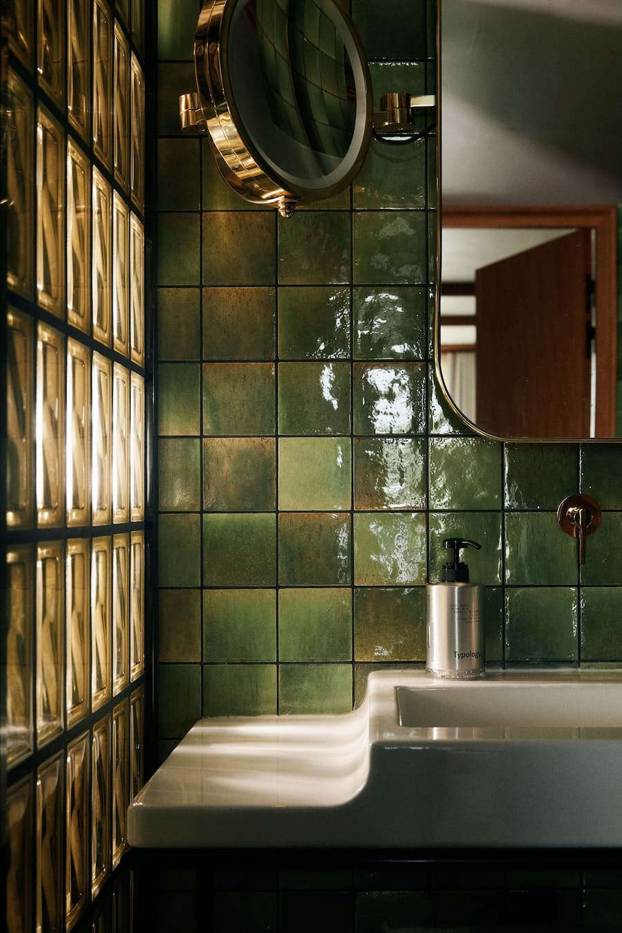 Glass block wall and green tile detailing inside La Fondation bathroom