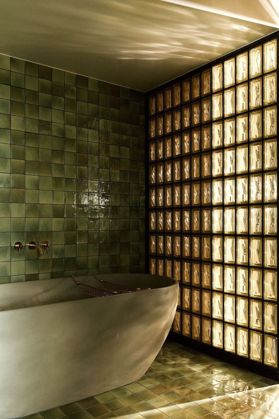 Freestanding bathtub within green tiled bathroom at La Fondation