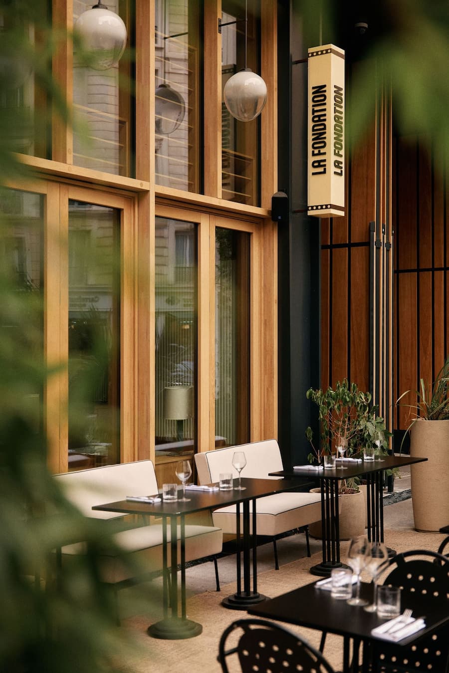 Elegant Paris restaurant terrace with warm timber facade and outdoor seating framed by greenery