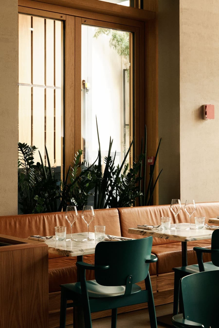Warm restaurant dining area with caramel leather banquette seating and natural daylight