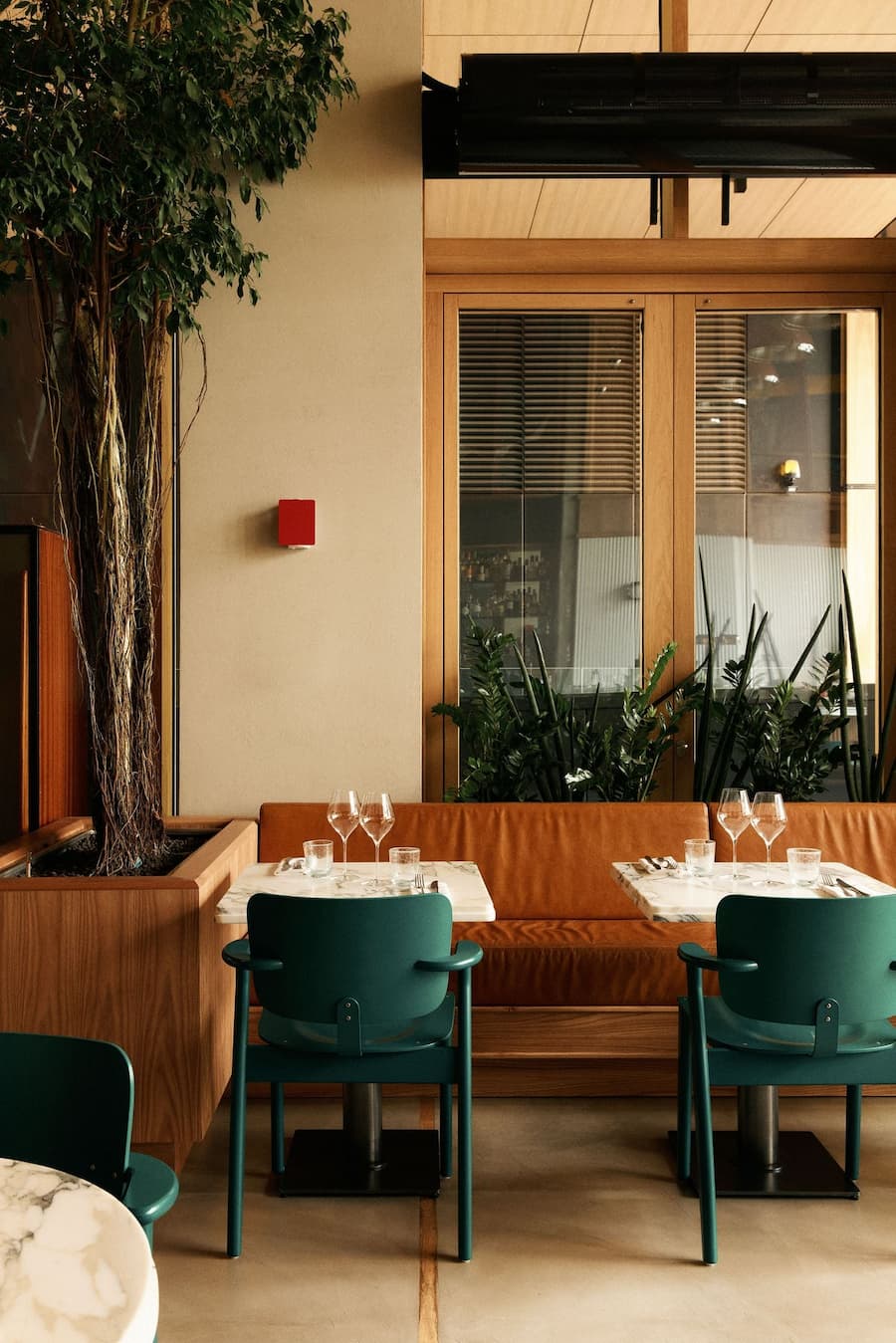 Refined Paris dining space with timber detailing, green chairs and marble-top tables