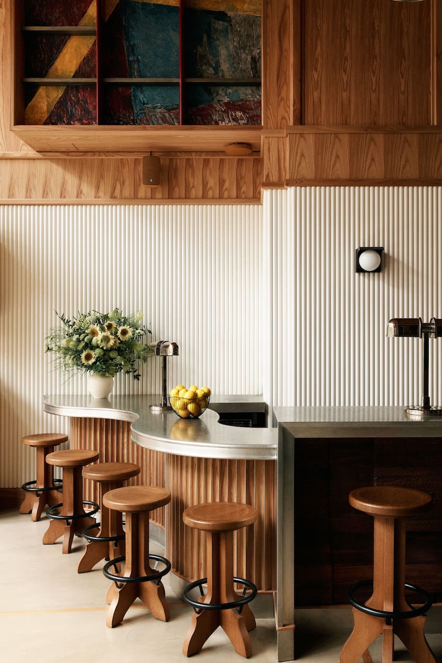 Sculptural curved bar counter with wood stools and textured wall panels