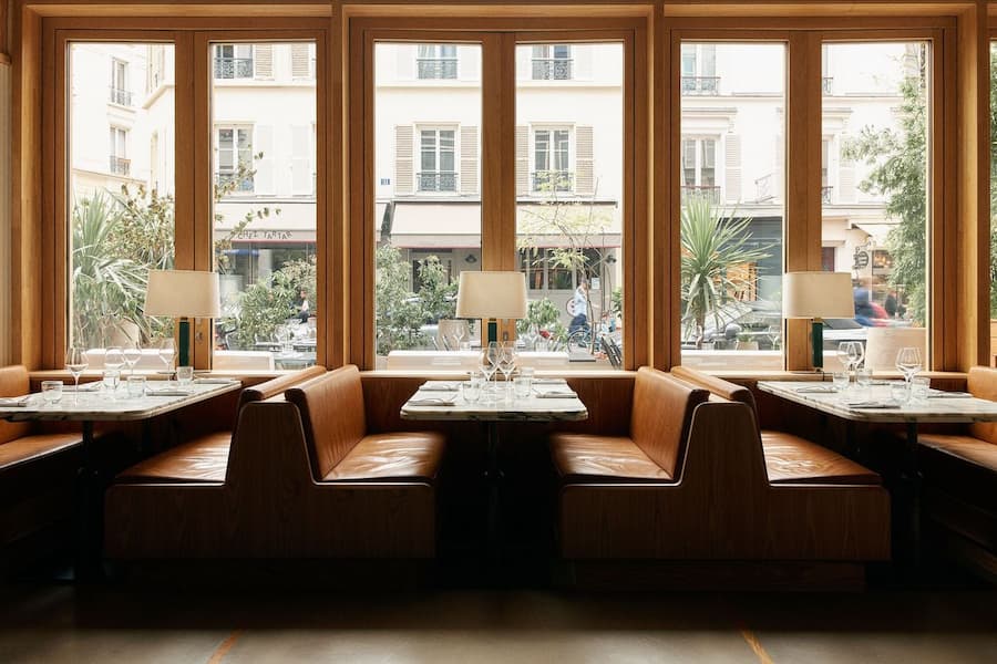 Cozy restaurant booth seating beside large Parisian street-facing windows