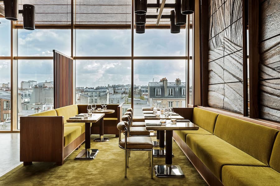 Modern rooftop dining space in Paris with panoramic city views and olive-green seating