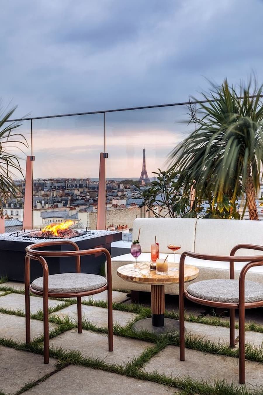 Luxury rooftop lounge in Paris with outdoor sofas and sunset city skyline