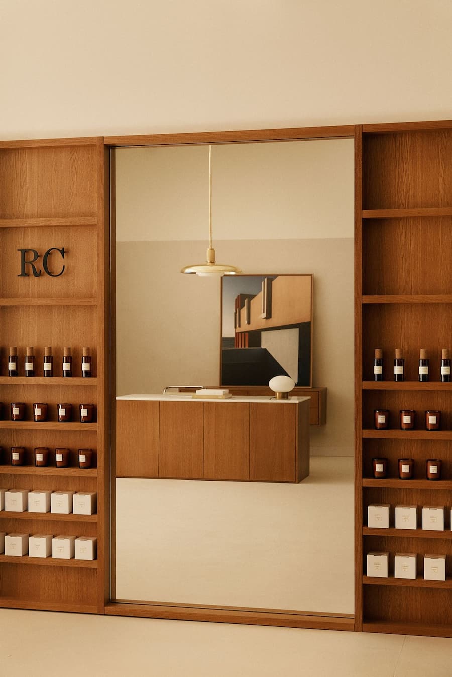 Minimalist retail interior with warm oak shelving, framed opening and curated product displays