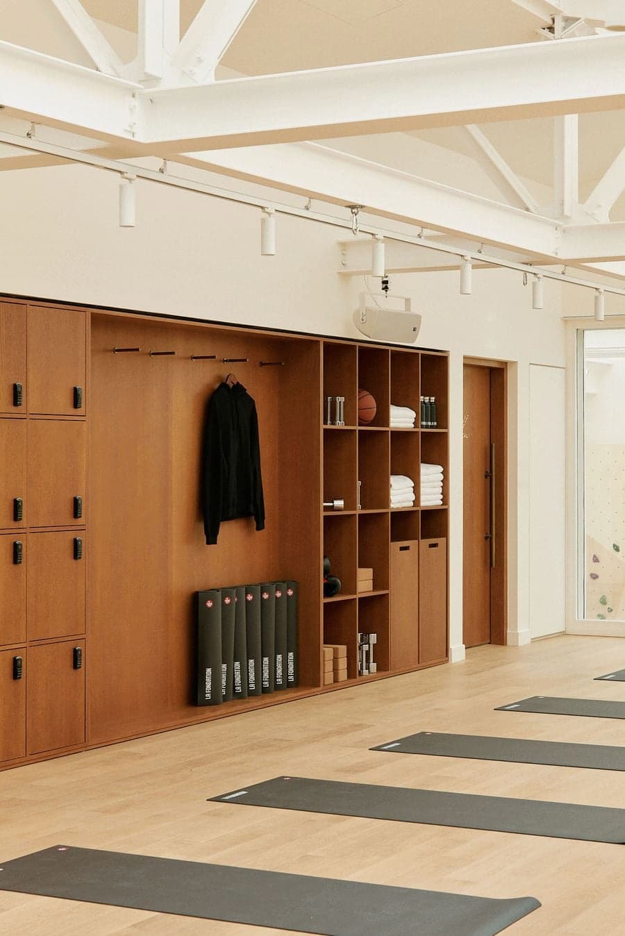 Wellness studio interior with wood lockers, open shelving and training mats