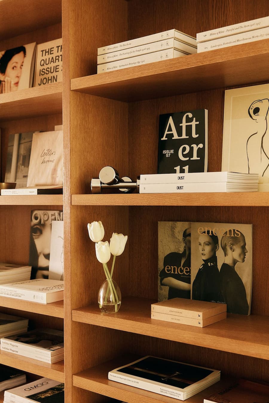 Editorial-style wood bookshelf with curated books, objects and minimalist retail styling