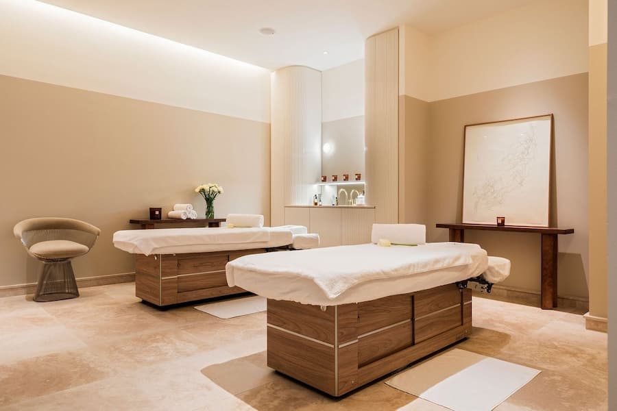 Calm spa treatment room with neutral tones, massage beds and soft ambient lighting
