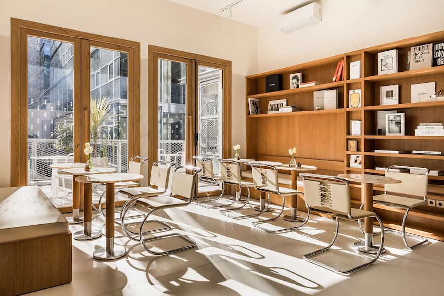 Sunlit café seating area with minimalist furniture and warm timber shelving
