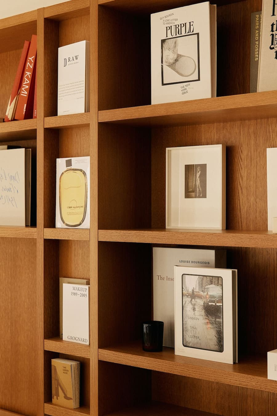 Curated wood bookshelf featuring art books, framed prints and decorative objects