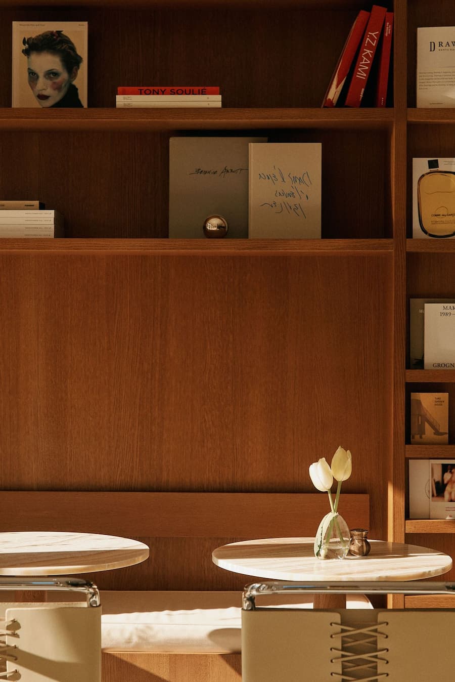Minimal café table seating with tulip flowers and integrated timber shelving backdrop