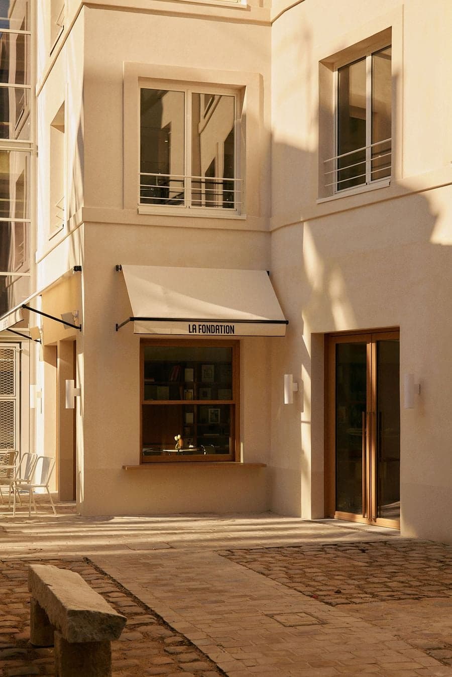 Sunlit courtyard hospitality architecture with minimalist facade, soft shadows and warm natural tones