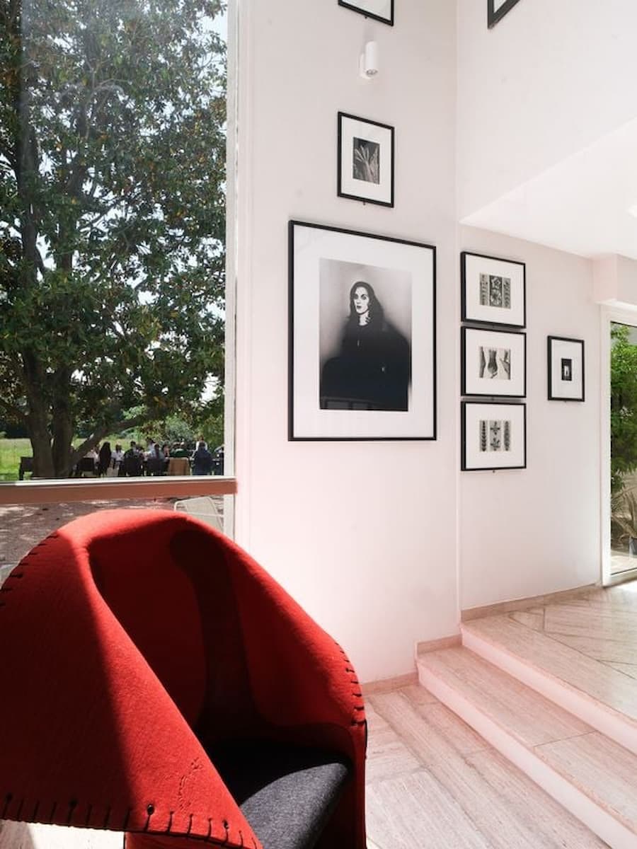 Gallery entrance at Casa Ideale featuring a sculptural red lounge chair and curated photography inside Villa Bank