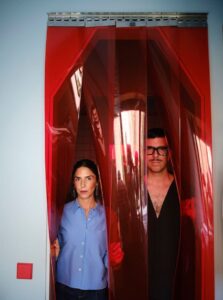 Studio Plutarco founders standing behind the custom translucent red vinyl entrance in the renovated Madrid villa.