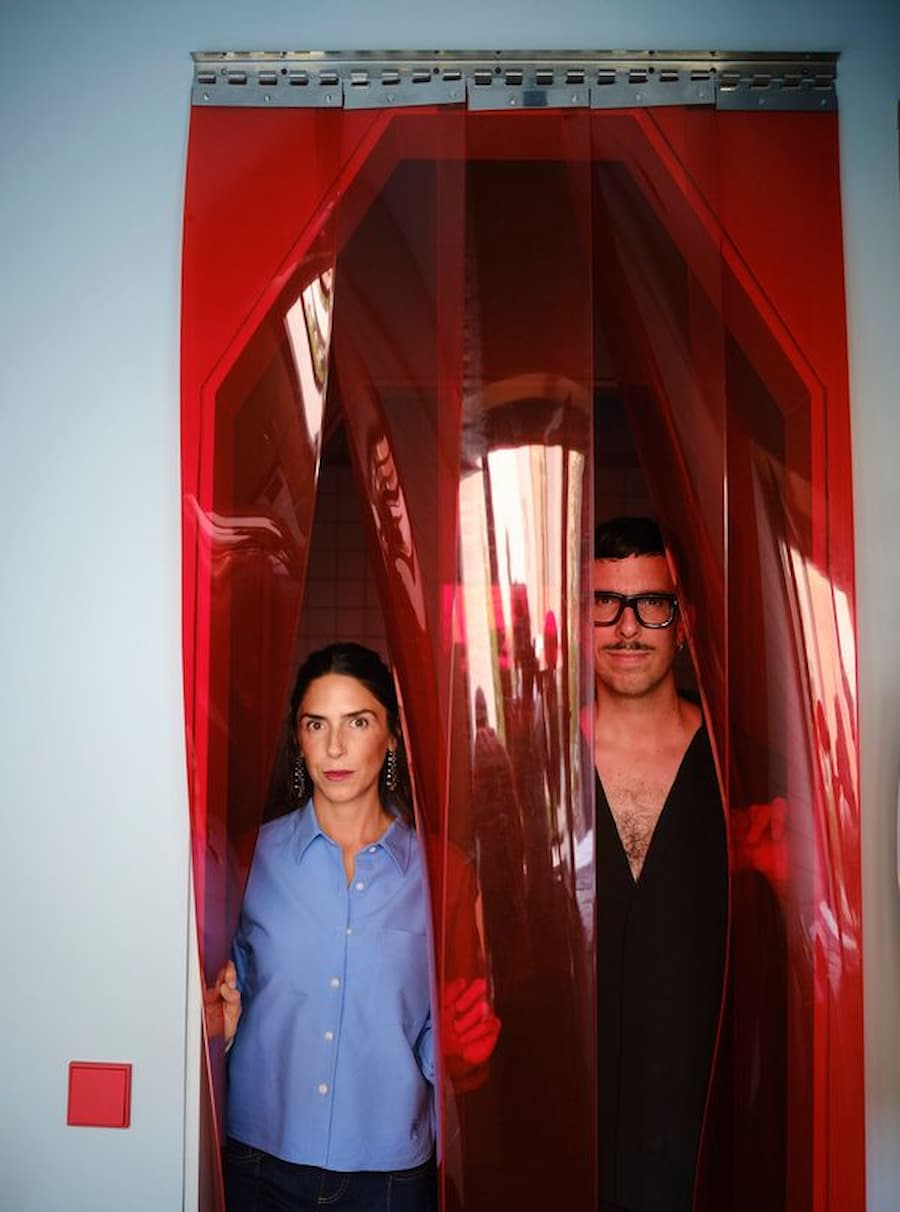 Studio Plutarco founders standing behind the custom translucent red vinyl entrance in the renovated Madrid villa.