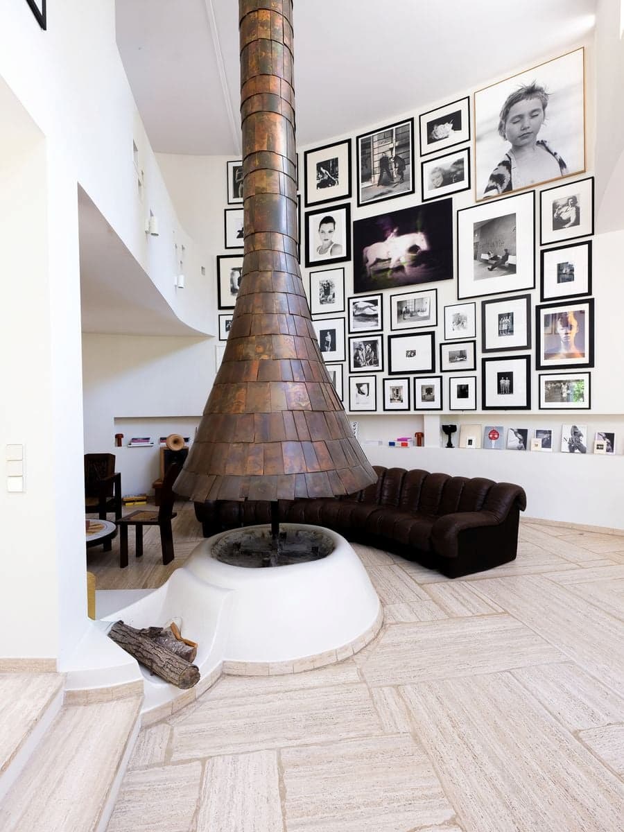 Double-height living gallery at Casa Ideale with Max Sauze suspended copper fireplace, De Sede DS-600 sofa and Carla Sozzani photography collection