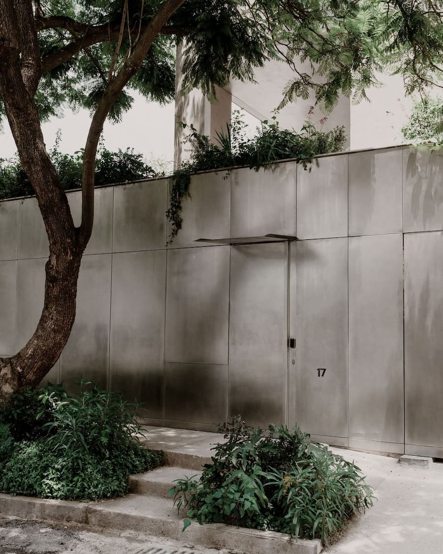 Garden approach leading to the concealed entrance behind a reflective metal facade