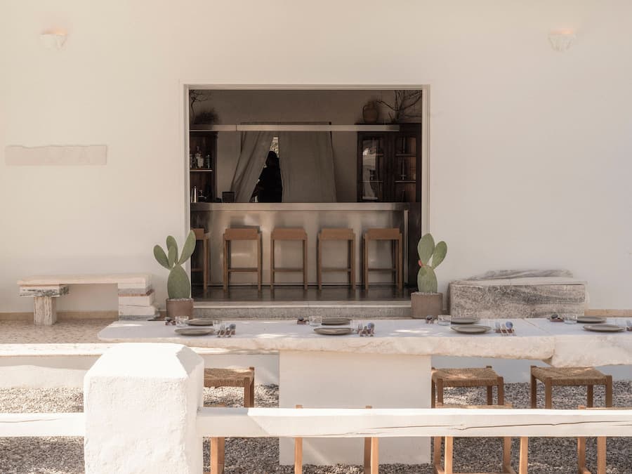 Open bar framed by a communal marble dining table within the restored courtyard of YAPA Antiparos restaurant 