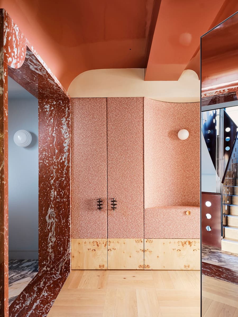 Custom cabinetry combining terrazzo, marble and burl wood beneath a lacquered ceiling.