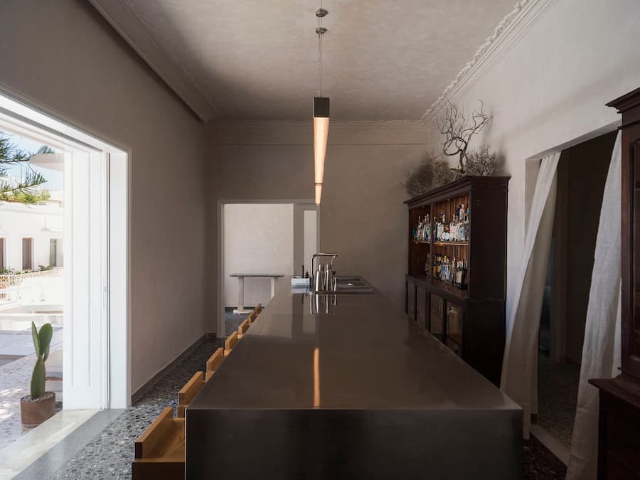 Open bar interior at YAPA Antiparos featuring stainless steel surfaces, handcrafted oak seating and restored Cycladic interiors in Greece